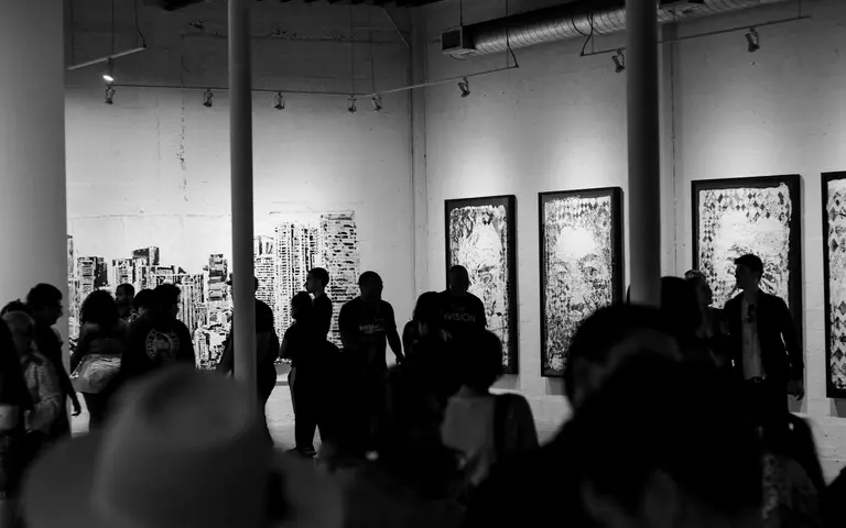 Posetioci u polumraku galerije razgledaju slike na zidovima tokom večernjeg programa
