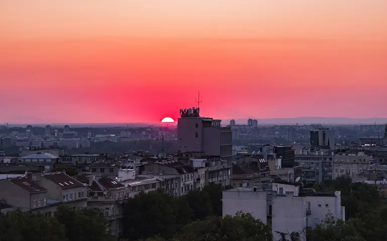 Krovovi Beograda u zalasku sunca pod narandžasto-ružičastim nebom